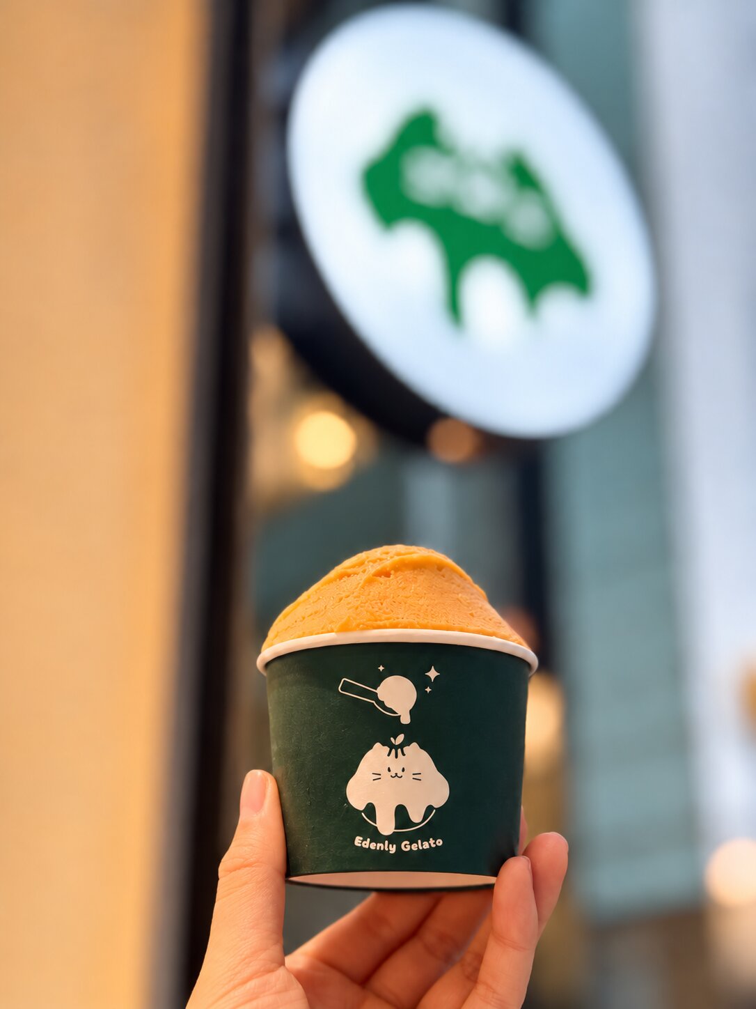Edenly Gelato cup with the Edenly shop sign softly blurred in the background